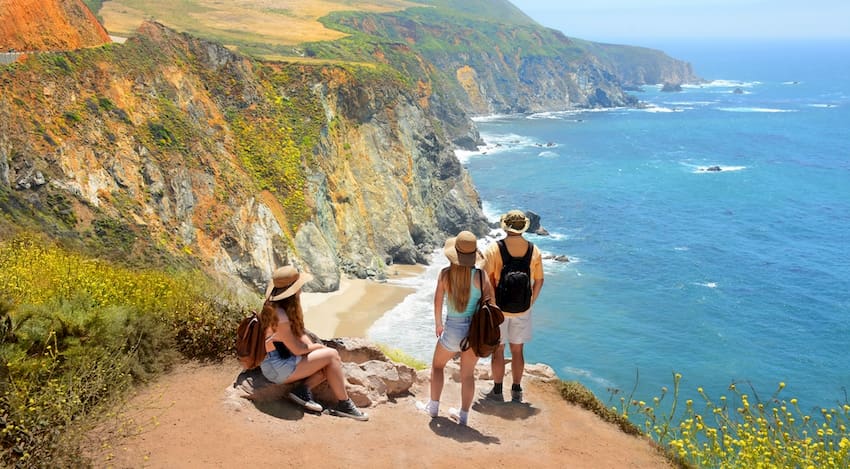 a group of hikers look over a bluff at a Pacific Ocean beach near Los Angeles, California