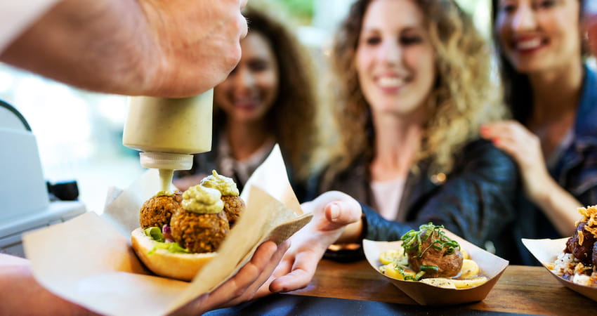 a group of women being handed food from a food truck