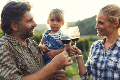 two people toasting wine glasses while holding child