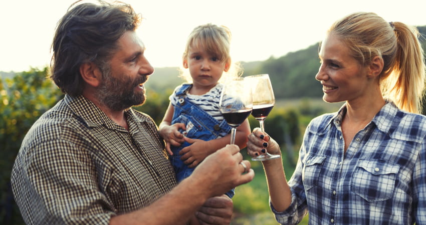 a woman and man toasting wine glasses while holding a child