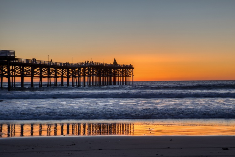 Picture of sunset at Mission Beach with the boardwalk and the water darkened in front of the sky