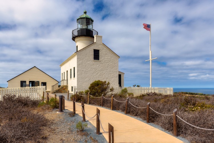 Image of Point Loma lighthouse, an old-fashioned white lighthouse with an American flag nearby
