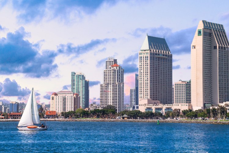 Image of San Diego coastline with skyscrapers and sailboat floating past