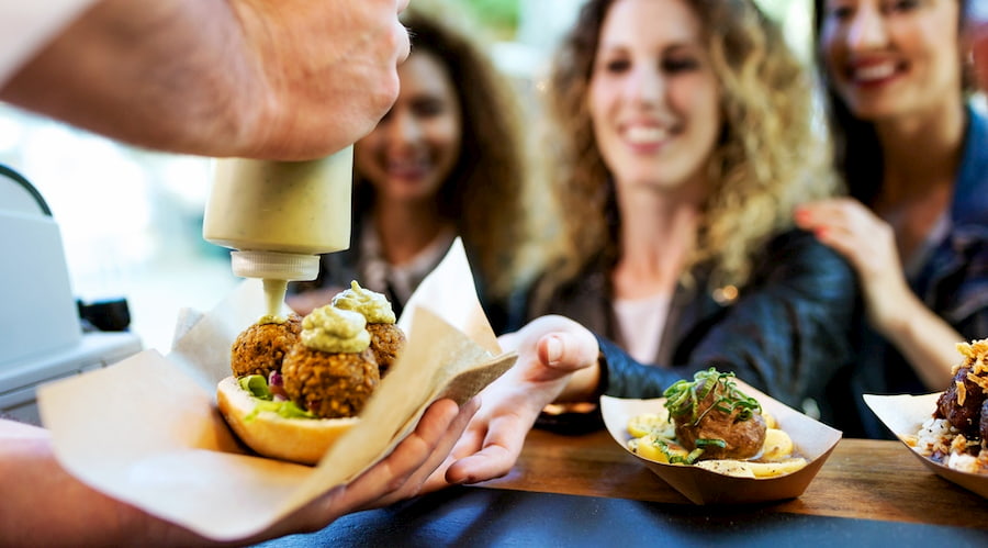 a group of foodies wait for a food truck chef to complete their falafel meal