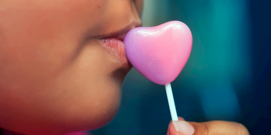 a toddler tastes a heart-shaped lollipop
