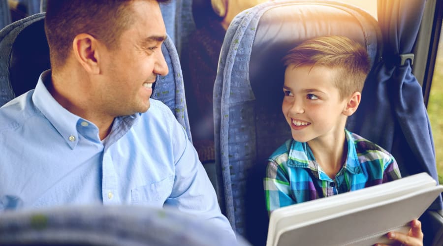 a student and chaperone smile and share a smart tablet while riding on a charter bus