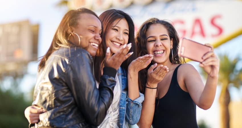 A group of young women taking photos in front of the Las Vegas Sign