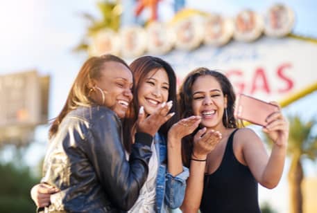 A group of young women taking photos in front of the Las Vegas sign