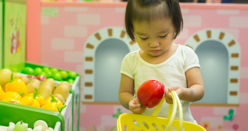 A small child pretends to shop in a play grocery store