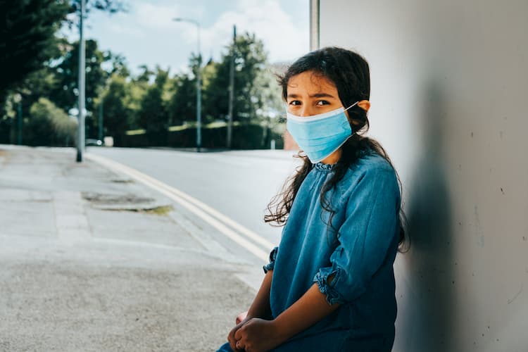 Little girl at bus stop wearing face mask