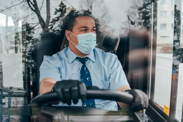 Bus driver wearing gloves and mask