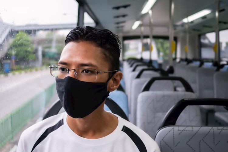 Young man wearing mask on charter bus 