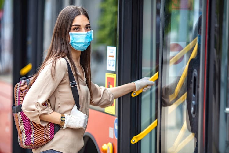 Woman boarding bus in gloves and mask