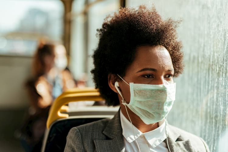 Woman wearing mask while listening to music on bus