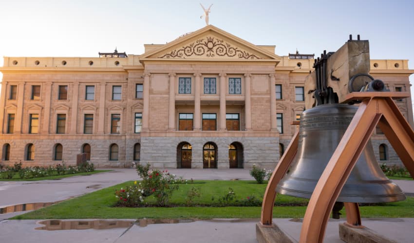 The exterior of the Arizona Capitol Museum, a big iron bell in the foreground