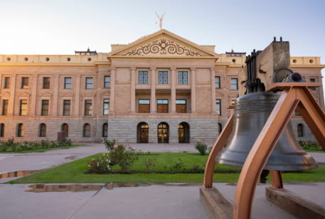The exterior of the Arizona Capitol Museum, a big iron bell in the foreground