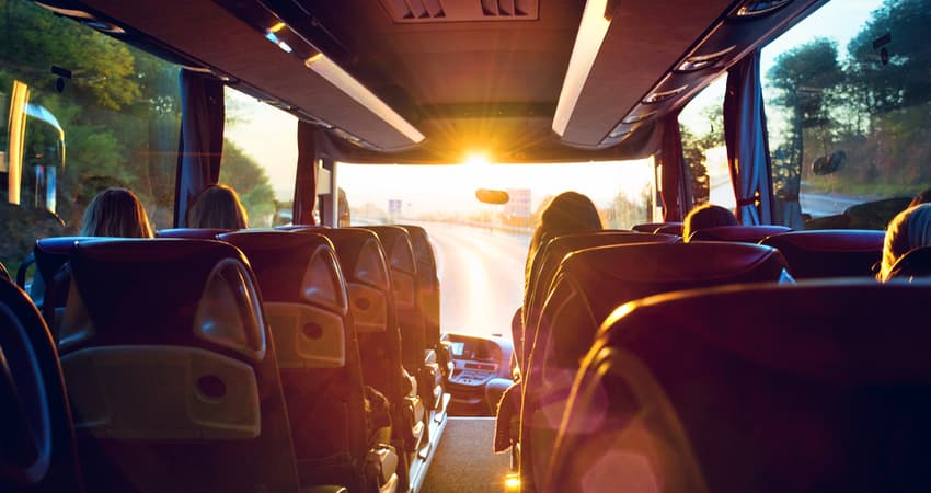 The inside of a charter bus while driving in the sunset