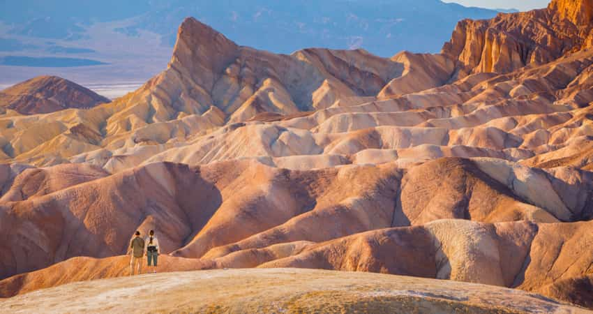 Two people standing in Death Valley National Park with mountains in the distance