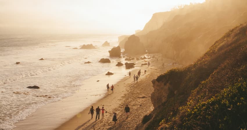 An aerial view of people walking along El Matador Beach at sunset