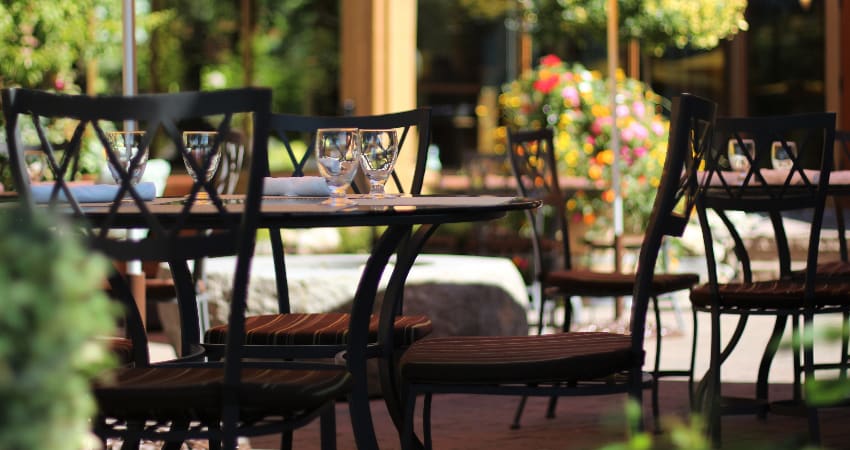 A shady patio of a restaurant is set for lunch