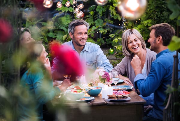 A group of dinner guests eat food in a garden dinning space