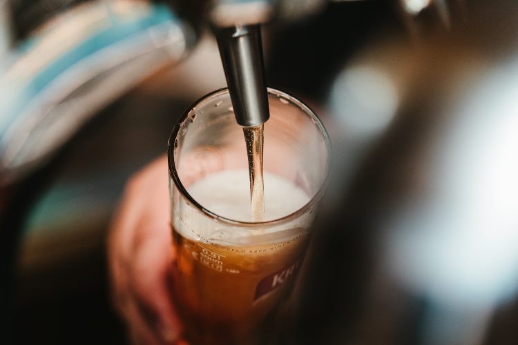 a bartender pours a beer into a glass