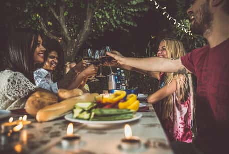 A group of friends dining in a garden and toasting wine