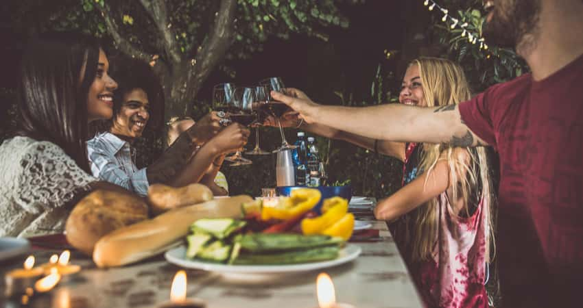 A group of friends dining in a garden and toasting wine