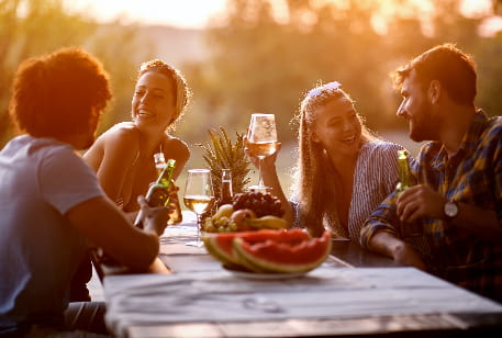 A group of friends dine at an outdoor table at sunset