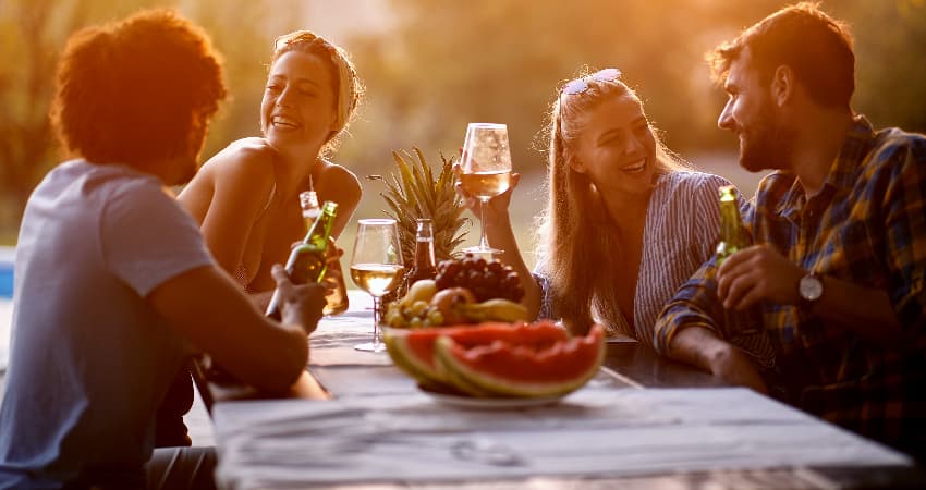 A group of friends dine at an outdoor table at sunset