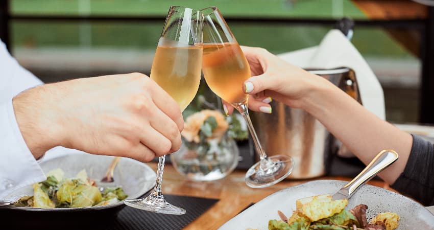 A couple toasts glasses of wine in an outdoor dining venue