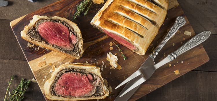 a few beef wellington slices on a wooden board