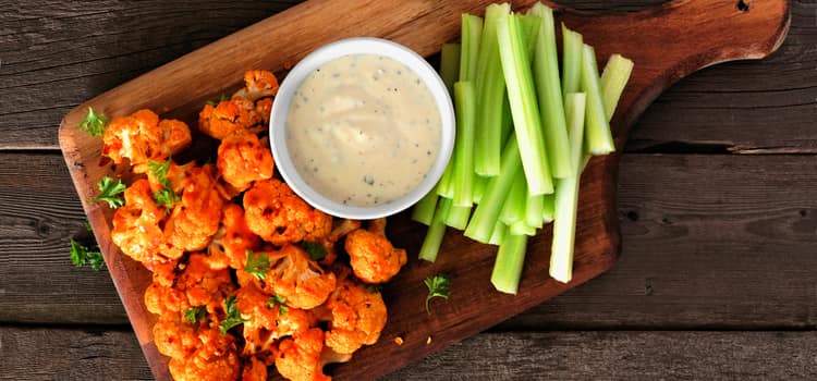 small boneless buffalo chicken bites with ranch dressing in a small bowl and celery sticks