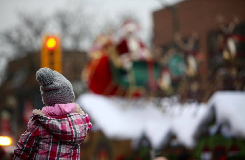 child wearing a winter hat watching a christmas parade go by