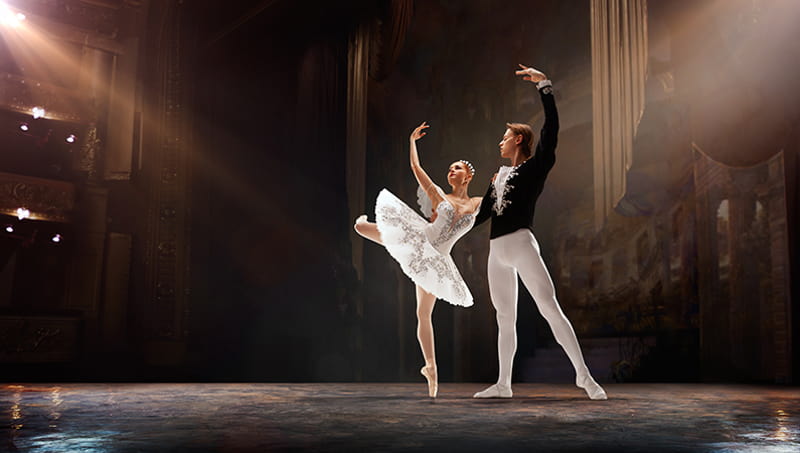 Two ballet dancers pose on a stage