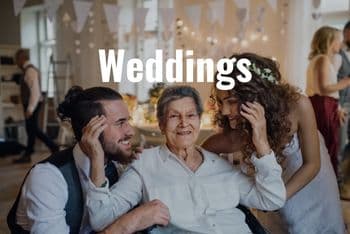 a couple hugging an elderly family member at a wedding