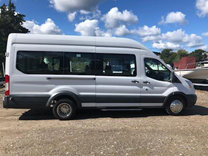 a small white minibus with a sliding door parked on pavement