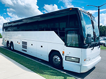 a plain white charter bus parked by a sidewalk