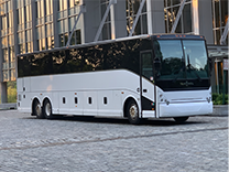 a plain white charter bus parked outside of a convention center